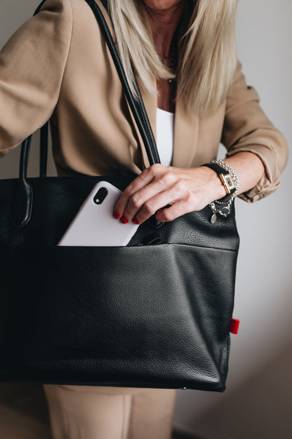 Große Businesstasche für Damen aus Leder in schwarz. Mit Laptopfach für 17 Zoll Laptop. Mit langen Henkeln als Umhängetasche zu tragen. Geräumige und intelligente Innenaufteilung. Innenfutter in pink aus reiner Baumwolle.